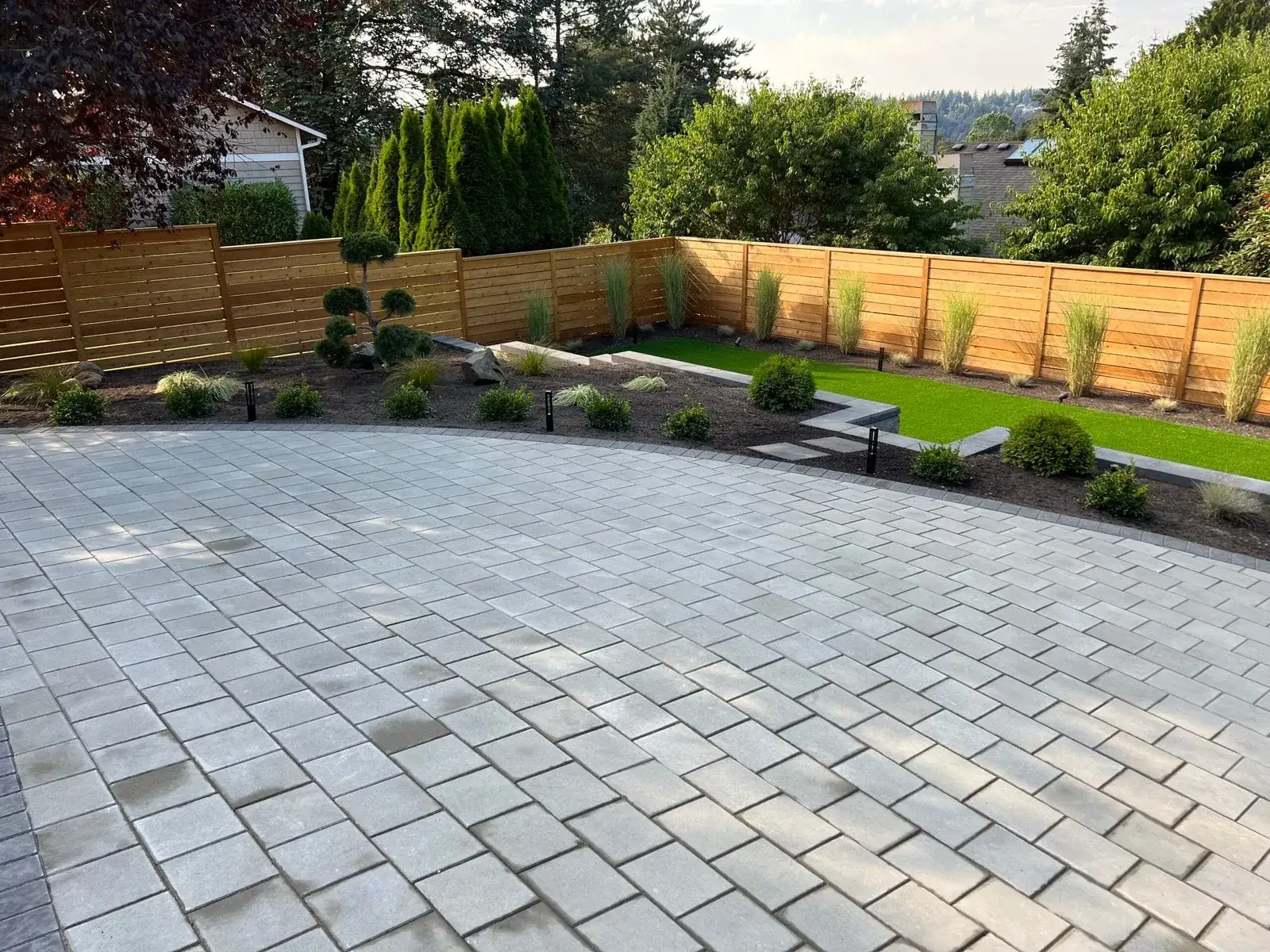 Finished back garden with a paver patio, artificial turf lawn and new cedar fencing