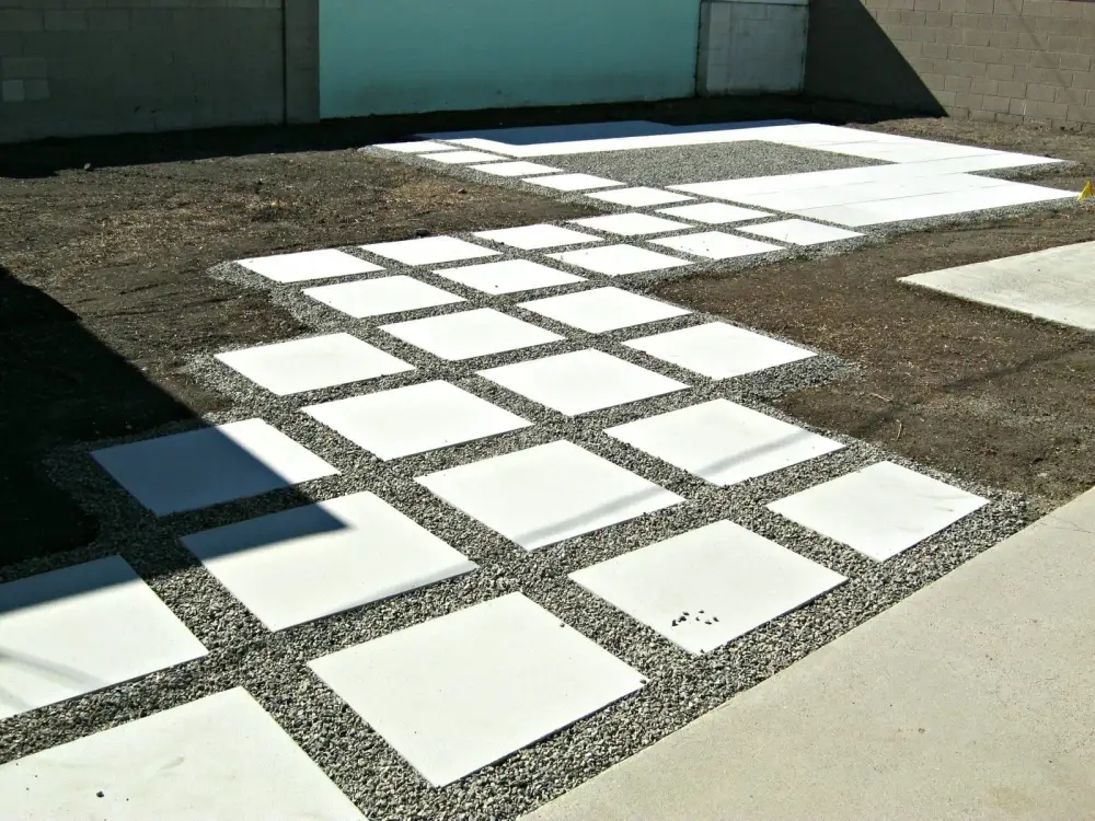 Oversized square concrete slabs set into a gravel bed forming a modern walkway