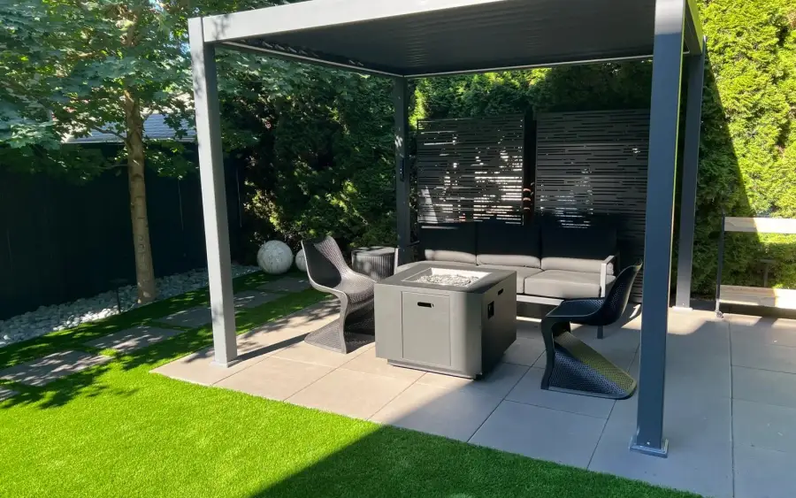 Modern aluminium pergola over an outdoor lounge with a fire table beside an artificial turf lawn